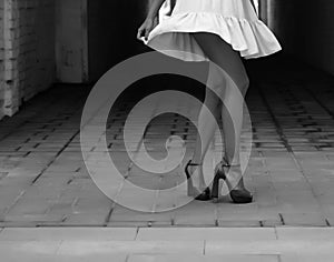 Women`s feet in heels in a dark alley of the city