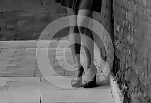 Women`s feet in heels in a dark alley of the city