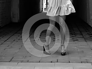 Women`s feet in heels in a dark alley of the city