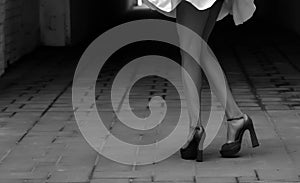 Women& x27;s feet in heels in a dark alley of the city & x28;black and white photo& x29;