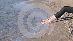 Women`s feet in leggins against the sea in sand beach.