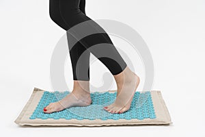 girl standing on applicators doing foot massage on a massage Mat photo