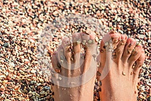 Women's feet on the pebbles beach