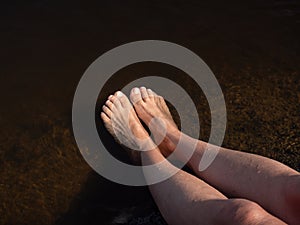 Women& x27;s feet are refreshed by bathing and splashing water in the lake