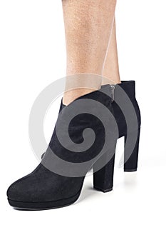 Women`s feet shod in black demi season high heeled ankle boots