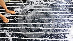 Women`s feet standing on a black old carpet with a very dirty white pattern