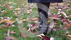 Women's feet walk on fallen autumn leaves. A woman walks in an autumn park