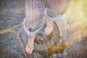 Women's feet in the water on a flooded beach, close-up. The girl stands on the stone bottom after the surf