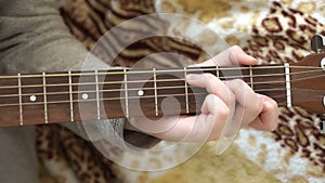 Women`s fingers on the strings of the guitar