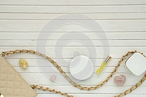 Women`s flatlay with handbag, cosmetics, perfume and minerals on white wooden background.