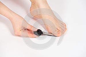 Women& x27;s foot on a white background, removal of rough skin on the big toe with a laser file, pedicure