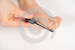 Women& x27;s foot on a white background, removal of rough skin on the big toe with a laser file, pedicure
