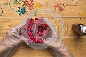 Women`s gloved hands hold a dyed rolled-up tie dye T-shirt. Flat lay