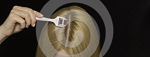 Women`s hair and mesoroller in hand on a black background. Care for the scalp, healthy hair