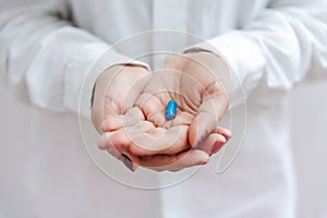 Women`s hand with blue pill, vitamin, capsule. Medical insurance, medical treatment concept. Disease, sick treatment, cold season