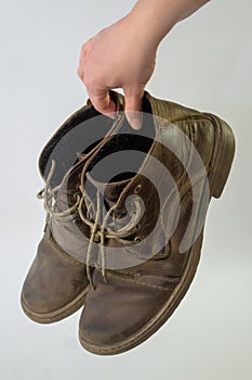 Ðº Women`s hand holds with disdain old men`s nubuck shoes, dangling shoelaces