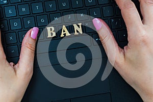 Women`s hand on the laptop keyboard with the letters BAN