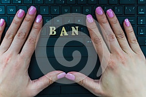 Women`s hand on the laptop keyboard with the letters BAN