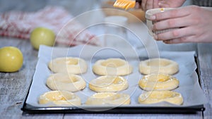 Women`s hand lubricate the buns with egg. Cooking open buns with apple Vatrushka - traditional Russian baking. Series.