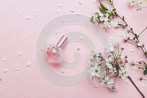 Women`s hand spray perfume. Flower arrangement. Flowers, fragrance, perfume on pink background