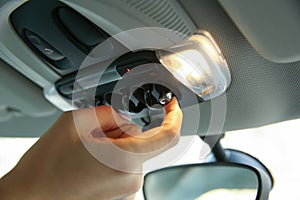 Women`s hand turns on the light in the car