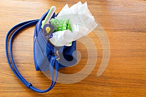 Women's handbag with items to care for the child: bottle of milk, disposable diapers, rattle, pacifier and baby clothes.