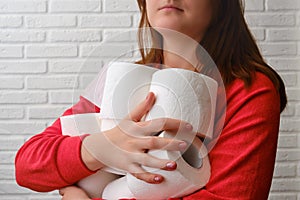 Women`s hands with an armful of toilet paper rolls, close-up. Problems with digestion, diarrhea, stomach pain in people
