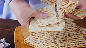 Women's hands break matzah at the Pesach Seder table