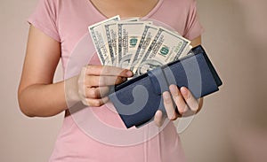 In the women`s hands is the bule leather wallet with a wad of hundred dollars