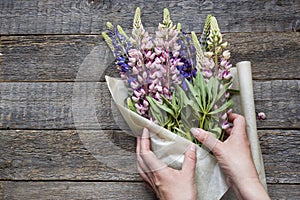 Women`s hands are collected in a bouquet of lupine flowers on a