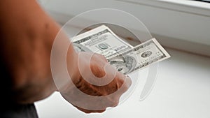 Women`s hands count dollar bills in front of them at the window