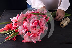 Women`s hands create a bouquet of flowers of gladiolus