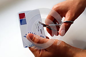 Women`s hands cut a plastic card with iron scissors