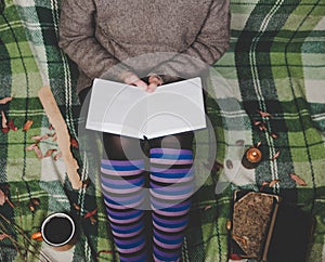 Women& x27;s hands and feet in sweater and cozy socks holding cup of