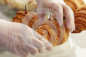 Women`s hands in gloves hold a croissant. Listing of products for sale. Business meetings and coffee breaks. Close-up