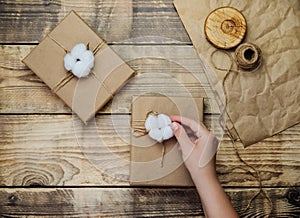 Women`s hands hold a box on a wooden background.The decor is made of cotton flowers.Christmas, birthday