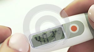 Women's hands hold an electronic thermometer, high body temperature, close-up