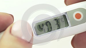 Women's hands hold an electronic thermometer, high body temperature, close-up
