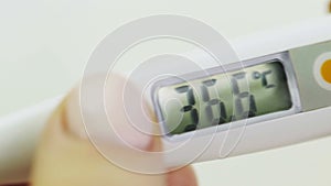 Women's hands hold an electronic thermometer, the temperature is normal, close-up