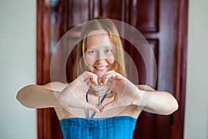 Women`s hands hold house key in the form of heart on the background of a wooden door. Owning real estate concept