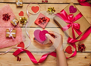 Women`s hands hold a paper heart on a wooden background. The concept of Valentine`s Day, Mother`s Day