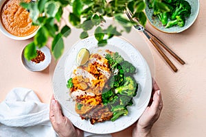 Women's hands hold a plate of chicken cutlet with katsu sauce.