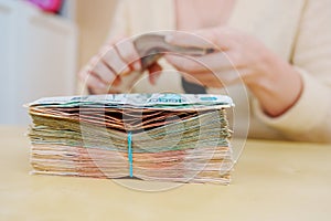women's hands hold a stack of rubles tied with a rubber band.