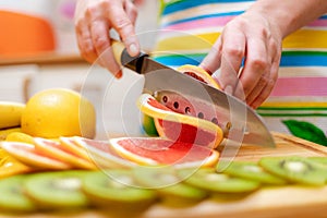 Women`s hands Housewives cut with a knife fresh grapefruit on th