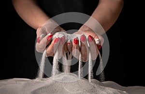 Women& x27;s hands keep sand in their palms and spilling grains of sand through their fingers. Hands of young woman play