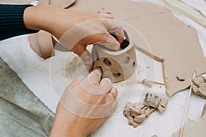 Women`s hands knead clay, drawing elements of the product. Production of ceramic products at the master class on ceramics