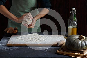 Women`s hands knead the dough. Baking ingredients on wooden table