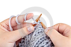 Women`s hands knit from grey wool on white background. Hand knitting