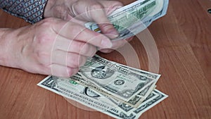 Women`s hands lay out American dollar bills in stacks. Counts the money