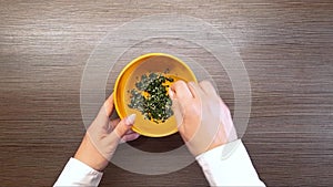 Women's hands mix herbs and garlic in a bowl. The view from the top